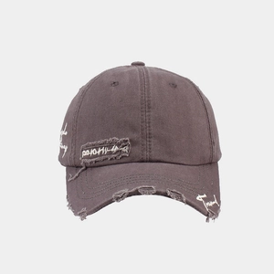 Detail of distressed charcoal baseball cap featuring vintage embroidery and ripped fabric edges