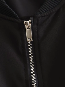 Macro detail of silver metal zipper and ribbed collar on black pilot bomber jacket