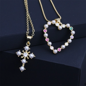 Détail de pendentifs dorés avec croix en perles et motifs de cœur en pierres colorées