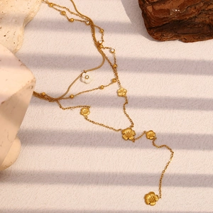 Detail view of gold layered necklace with white clover pendant on elegant stone