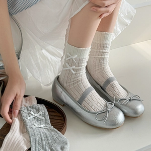 White ribbed crew socks with bow accents paired with silver Mary Janes in a top-down view