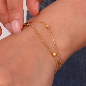 Minimalist double-layered gold snake chain bracelet with cubes on model's wrist