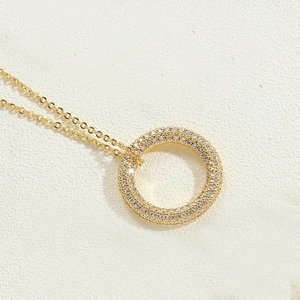 Detailed close-up of a 14K gold plated circular pendant necklace with pavé set zircons