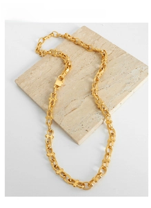 Detail of gold-plated geometric link chain necklace on white marble background