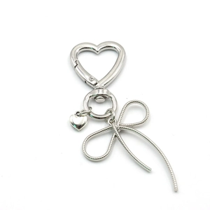 Detail of silver heart-shaped carabiner with metal bow pendant and heart charm