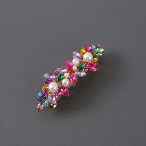 Detail of gold hair clip with colorful leaf-shaped rhinestones and white pearls