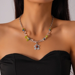 Détail du collier avec pendentif fleur, note verte et perles en verre transparentes