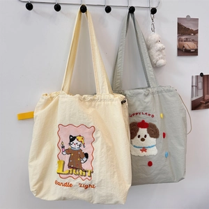 Detail of embroidered canvas tote bags with drawstring closure and cute animal illustrations