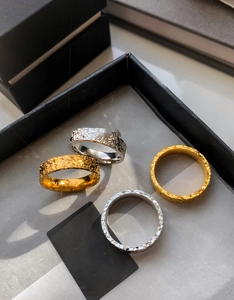 Detailed macro view of 18k gold and silver pleated rings with hammer texture in a black gift box