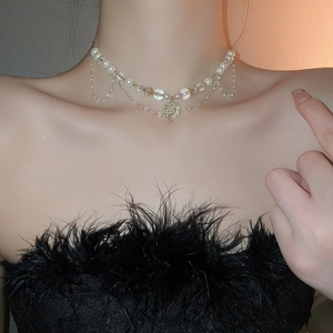 Détail d'un collier ras du cou multicouche en perles avec pendentif cœur en cristal et or
