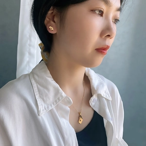 Close-up of golden titanium steel animal pendant necklace and earrings set on a model