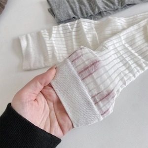 Detail of sheer vertical stripe texture and ribbed cuffs on thin white and grey socks