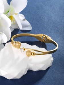Detailed view of a gold bangle with a sparkling zircon and matte gold bead accents