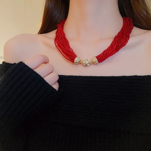 Detail of red multilayer seed bead necklace with gold rhinestone clasp on model