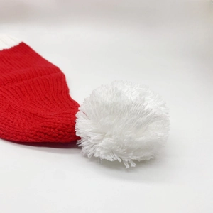 Gros plan d'un bonnet de Noël tricoté rouge avec un pompon blanc doux en laine