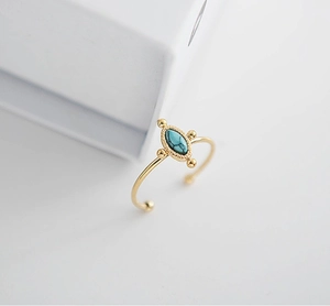 Close-up of gold 18K stainless steel open ring with oval peacock turquoise and bead trim
