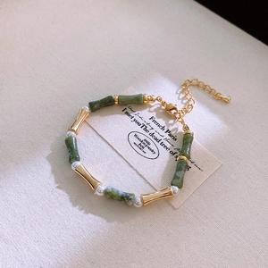 Close-up of vintage gold metal bracelet with green bamboo beads and white pearls