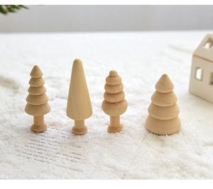 Close-up of four assorted natural wooden mini Christmas tree figurines on white snow