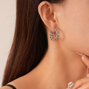 Macro view of silver chain earrings with pavé zircons on model ear
