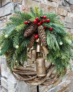 Macro detail of rustic Christmas wreath with green pine, red berries and gold metal bells