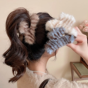 Détail de trois pinces à cheveux en peluche avec motifs marron, crème et bleu-gris doux