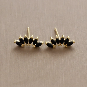 Detailed macro view of fan-shaped gold stud earrings with black marquise-cut stones
