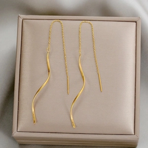 Boucles d'oreilles pendantes vagues dorées avec perles dans une boîte à bijoux