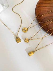 Detail of four gold stainless steel pendants with small zircons on a delicate chain