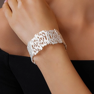 Detailed view of silver matte cuff bracelet with organic irregular hollow floral patterns