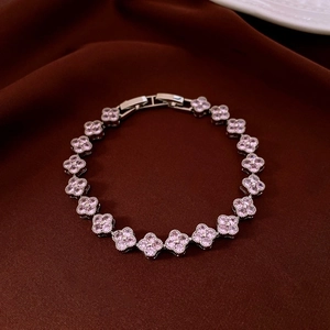 Détail du bracelet trèfle avec zircons roses sur fond en velours élégant et raffiné