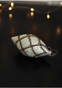 Macro view of matte cream spindle ornament with brown bead lattice and white snowflake details