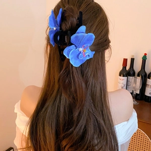 Elegant blue orchid hair claw clip with pearl center worn in a half-up hairstyle