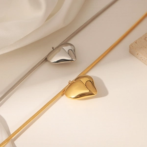 Minimalist heart pendant necklaces in gold and silver with snake chain on silk background