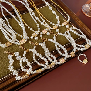 Close-up of 18k gold plated pearl necklace set with square gemstone on green velvet
