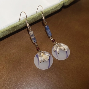Detail view of ethnic drop earrings with blue marble stone, resin disc and cream tassels