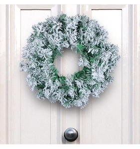 Close-up of frosted Christmas wreath with artificial pine needles on a white wooden door