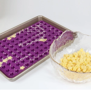 Macro shot of purple star silicone mold on metal tray with finished yellow star candies