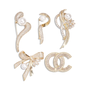 Five assorted 14k gold plated brooches with high-quality pearls and zircons on white backdrop