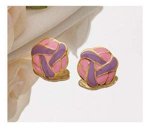 Macro shot of purple and pink enamel floral stud earrings with gold plating on mirror
