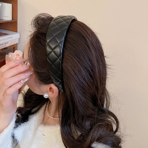 Detail of black quilted leather headband with padded design for a face-shaping effect