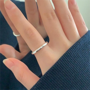 Minimalist 925 sterling silver smiley face ring on model hand with blue background