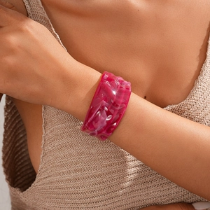 Detail of wide fuchsia acrylic bangle with marble texture worn on model wrist