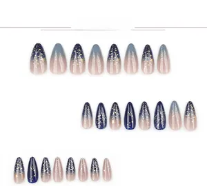 Detail view of almond press-on nails with blue gradient galaxy and gold star patterns