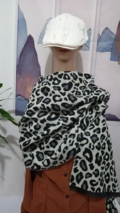 Detail of black and white leopard print thick scarf draped on a mannequin with beret