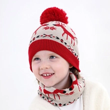 Close-up of red and beige knitted Christmas set with reindeer patterns and pom pom