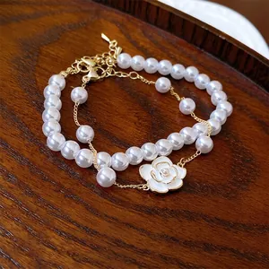Elegant double-layer pearl bracelet with a white camellia pendant and gold-tone hardware