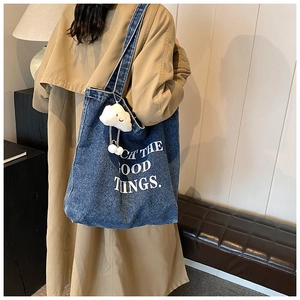 Détail du sac cabas vintage en jean avec broderie blanche et porte-clés nuage en peluche