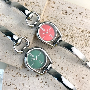 Close-up of vintage silver bracelet watch with red and green dials on stone background