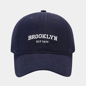 Close-up of white Brooklyn EST 1631 embroidery on a premium navy blue cotton baseball cap