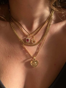 Close-up of layered 18k gold plated necklaces with heart, ruby, and smiley face charms